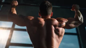 A muscular male athlete performing a pull-up exercise