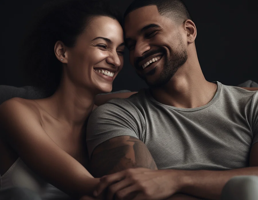 A cheerful man and woman sit on a couch, sharing smiles and enjoying each other's company.
