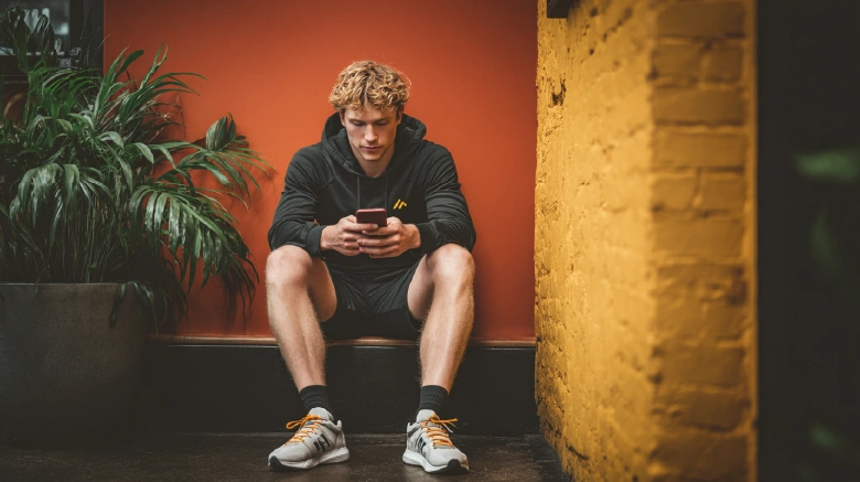 Caucasian Athlete seated with phone