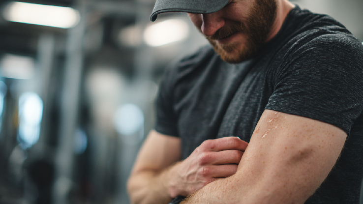 Bodybuilding man flexing arm at gym, fitness, strength training, muscular physique, professional gym environment.