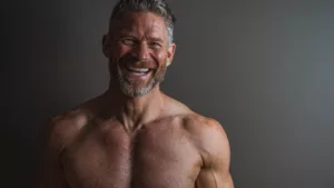 A man smiling confidently showing his muscular upper body after using trusted SARMs supplements.