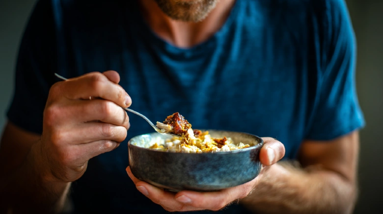 6 close up image of a fit Canadian man eating a simple chicken meal in a small bowl